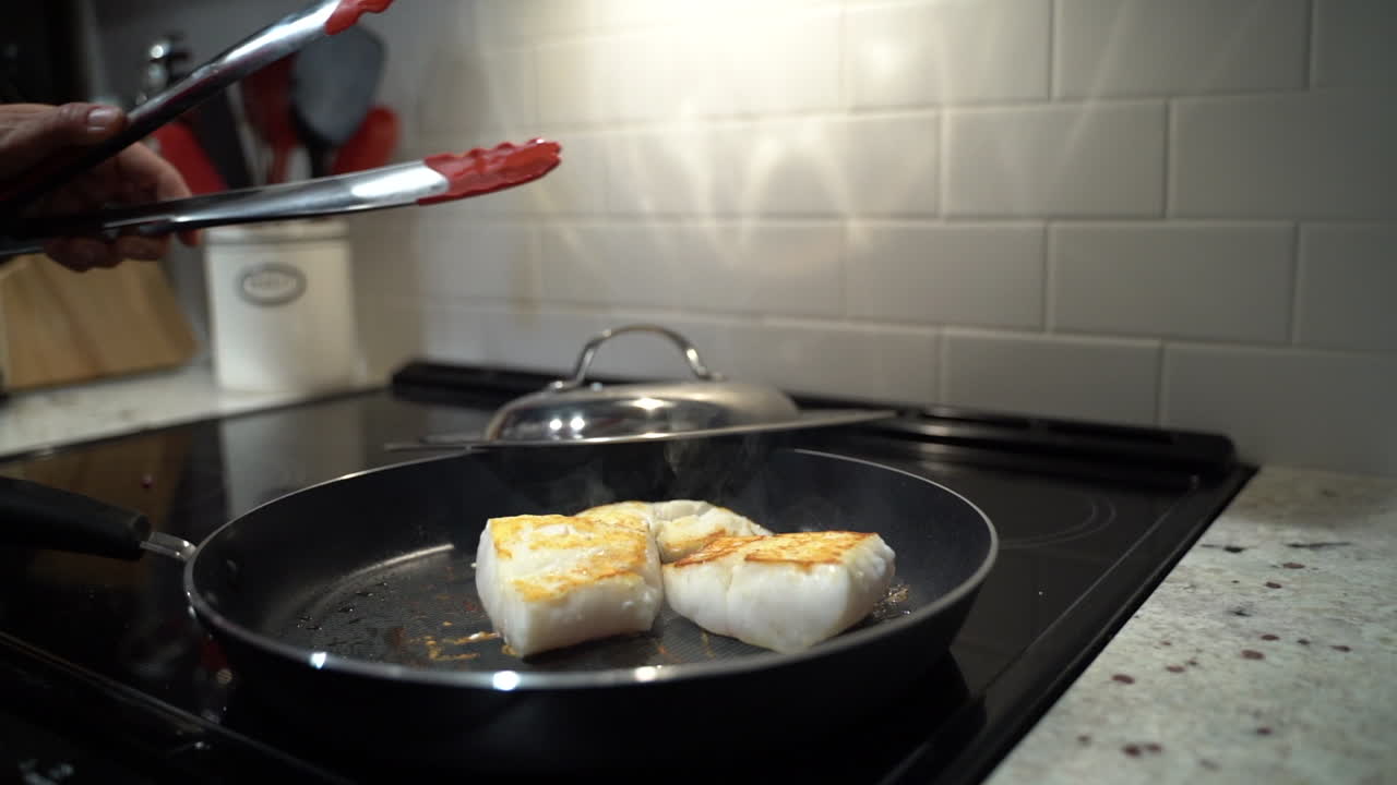 Fish filet sizzling and steaming in a pan on the stovetop
