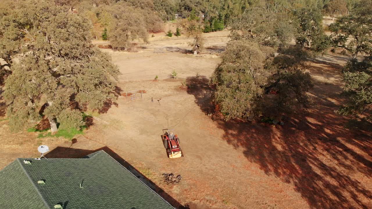 시골 농장을 돌아다니는 빨간색 트랙터를 따라 다니는 공중 드론