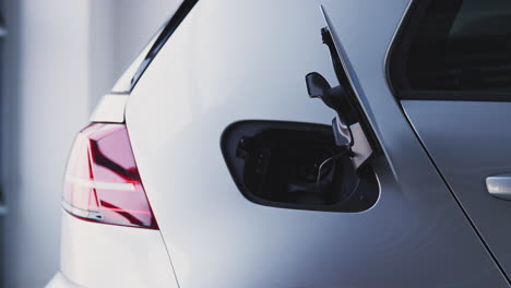 cerca de la mano quitando el cable de energía de un coche eléctrico ecológico de cero emisiones