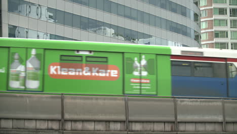 bts skytrain passes on the railway in bangkok, thailand with modern building structure in the background - low angle shot