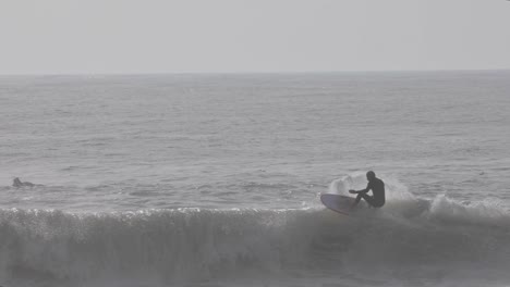 surfer man surfs the wave at carcavelos surf spot in cascais