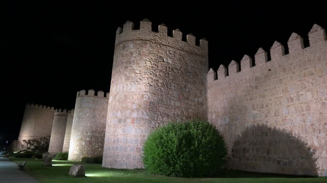 A nighttime scene of Avila's historic old town, highlighting the illuminated, UNESCO-listed medieval walls in Spain.