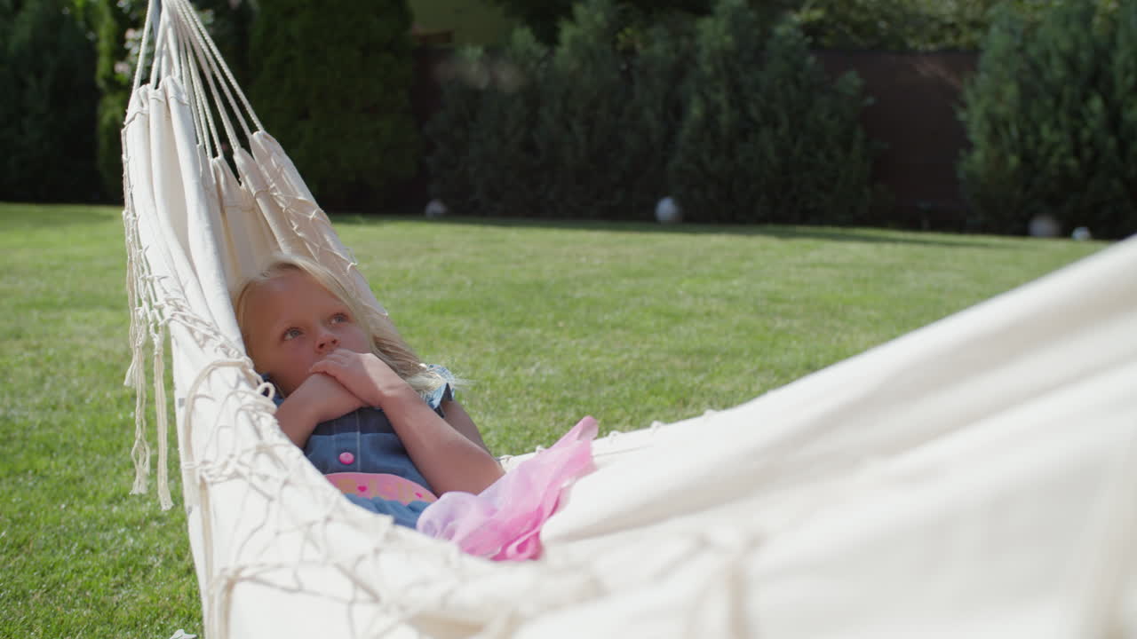 Child daydreaming in a garden hammock