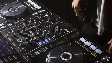 Close up DJ's hand turning knob and jugling between two deck of dj instrument