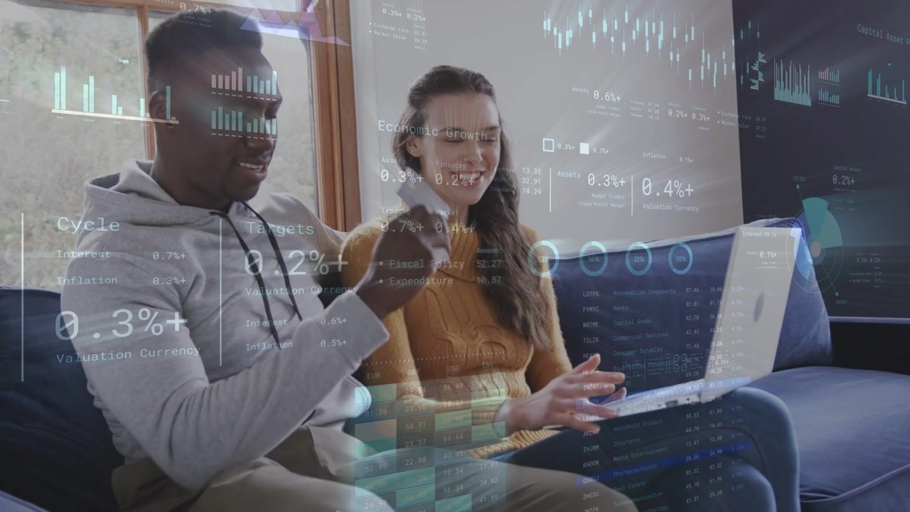 Couple on couch, woman typing initiating finance HUD animating charts over laptop checking finances