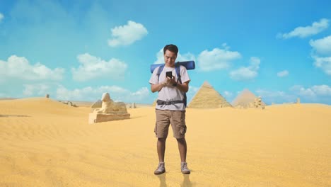 full body of asian male hiker with mountaineering backpack enjoy using smartphone while traveling in pyramid of giza