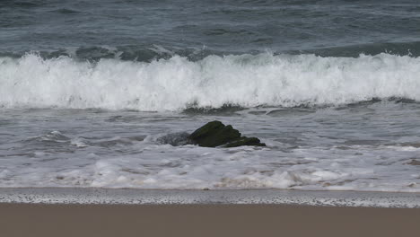 breaking waves over a rock on to beach at the north atlantic coast