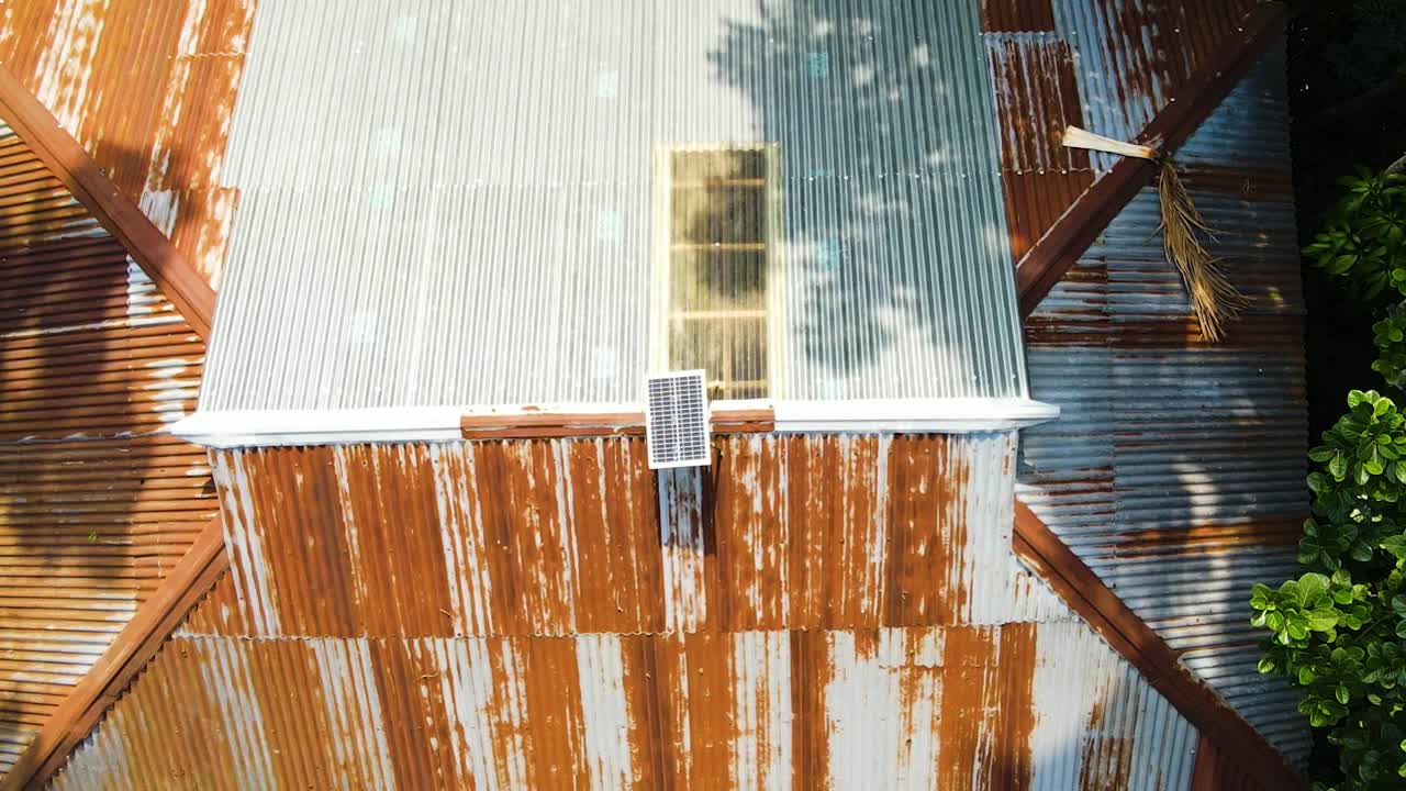 Solar panel getting sunlight on a rural tin shed house roof in remote area in South Asia, Bangladesh