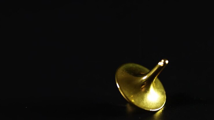 Close-up of gold tops spinning gracefully on a dark background, showcasing their reflective surfaces.