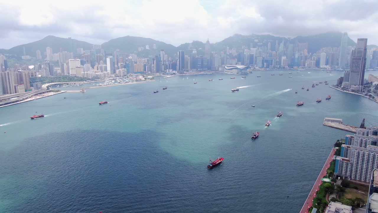 convoy de barcos de pesca locales que causan en la bahía victoria de hong kong, con el horizonte de la ciudad en el horizonte, vista aérea