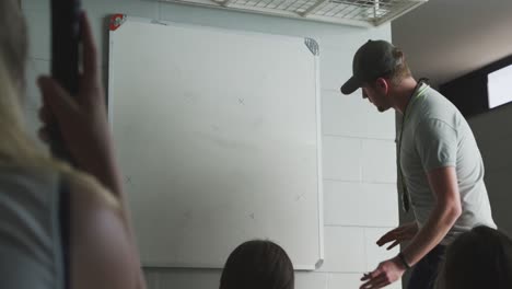 entrenador de hockey explicando el plan de juego con las jugadoras en el vestuario