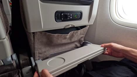 passenger unfolds and uses airplane tray table