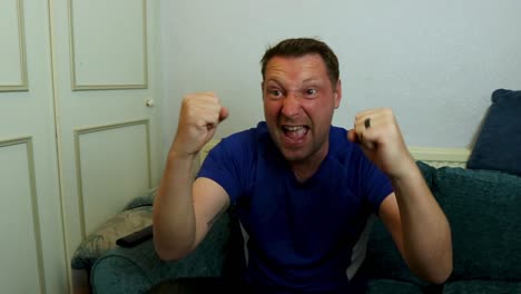 man watching sports on tv wearing a blue sports top