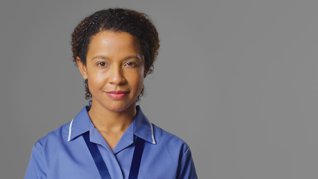 retrato de estudio de una enfermera seria vestida de uniforme ante la cámara contra un fondo gris