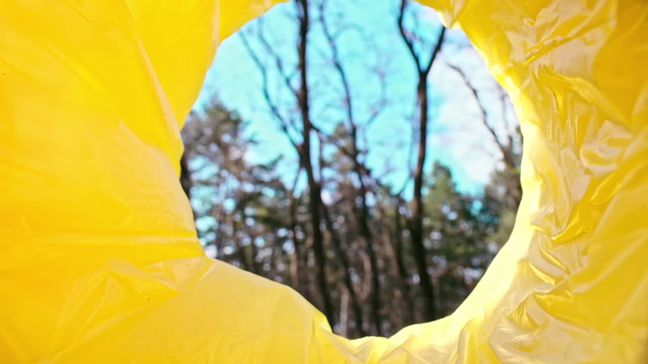 Man throwing a green plastic bottle into a trash can. View from inside the can. Slow motion