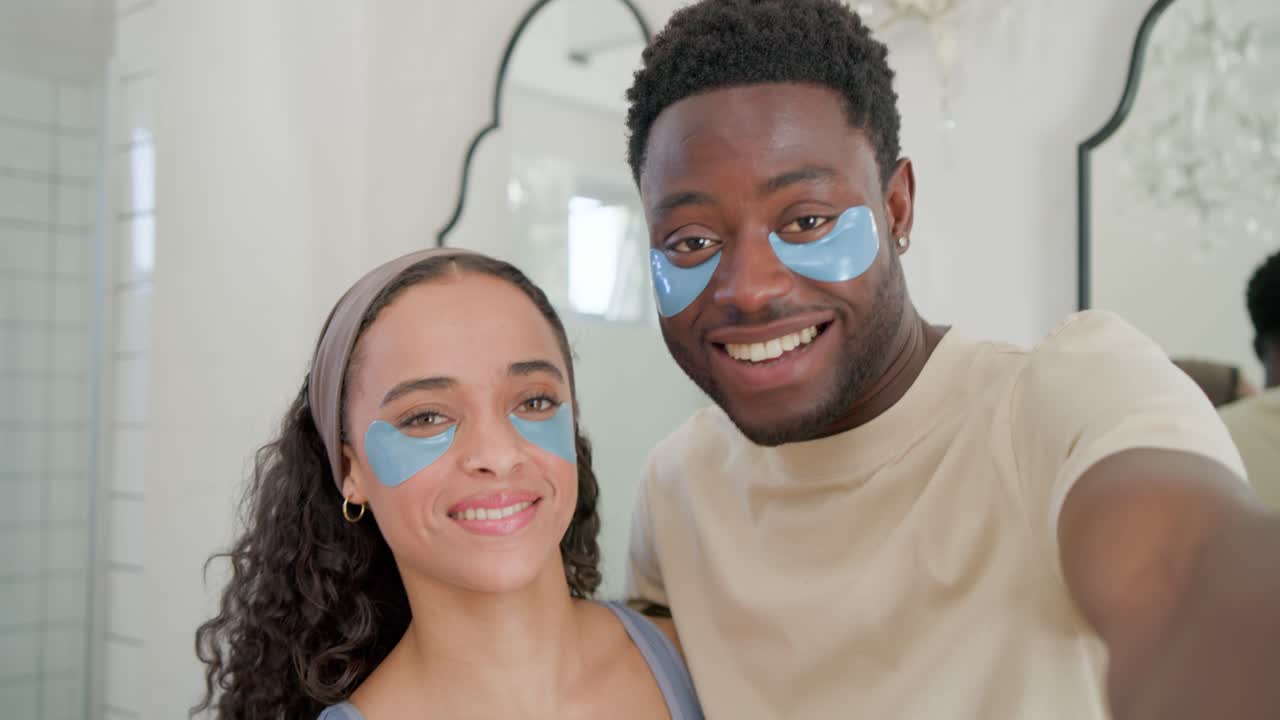 African American couple holding phone at vanity adjusting blue undereye patches to capture moment