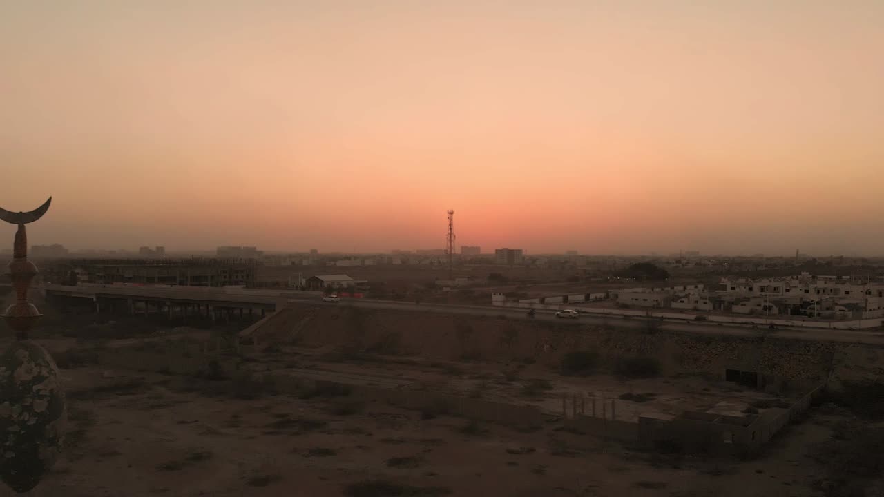 vista aérea del minarete de la mezquita cerca de la autopista en karachi contra el cielo amarillo anaranjado del atardecer