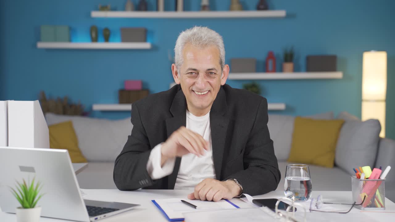 홈 오피스 직원 남자가 카메라를 쳐다보며 페이스타임을 하고 있습니다.