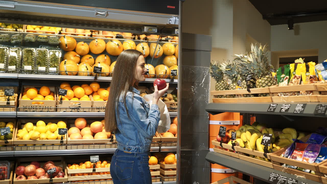 Beautiful young woman shopping for fruits and vegetables in a production department. Grocery store. Supermarket. Healthy lifestyle.