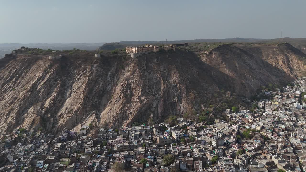 Overhead shot of the dense, maze-like residential areas at the base of a fortified hill.