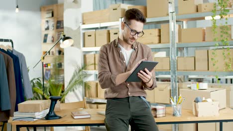 caucasian designer man using a tablet in a fashion clothing store