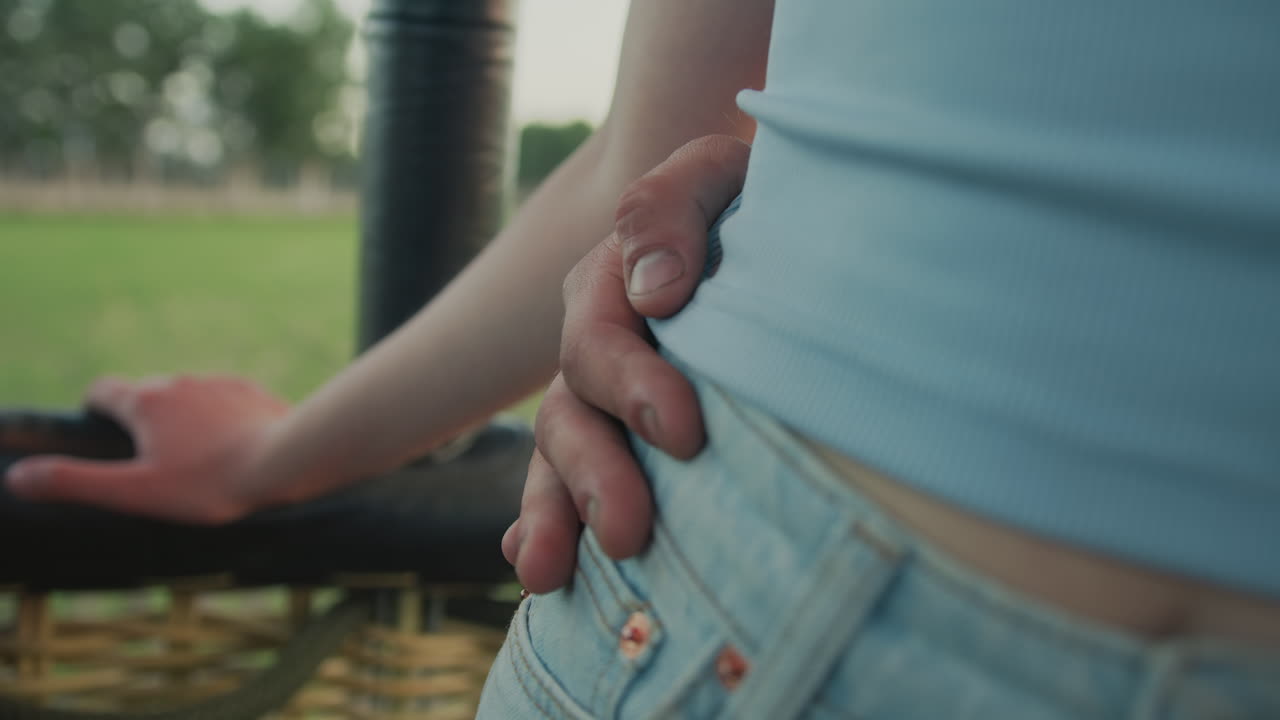 close up of couple standing together in moving hot air balloon as hand gently rests on waist while flying over vast green farmland under soft sky during peaceful afternoon outdoor adventure