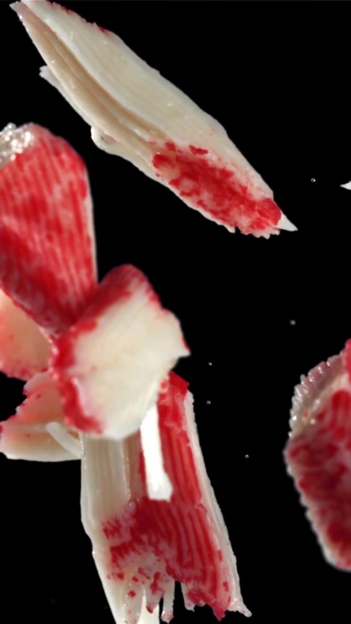 Imitation Crab Sticks Falling in Slow Motion Against Black Background