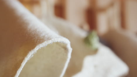 close up of wool hat edge with dry leaf resting gently on soft fabric surface, bathed in warm sunlight with blurred background and cozy indoor lighting creating calm peaceful mood of quiet stillness