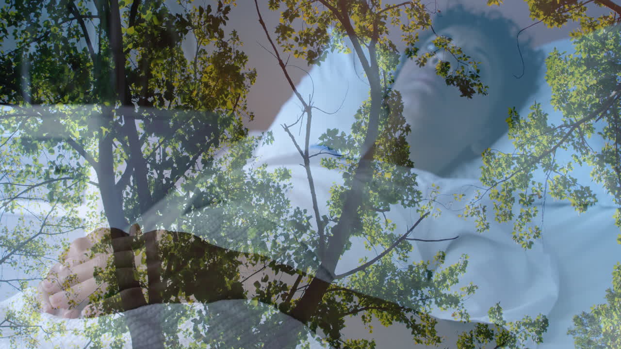 Animation of tree branches and leaves overlaying person resting with closed eyes