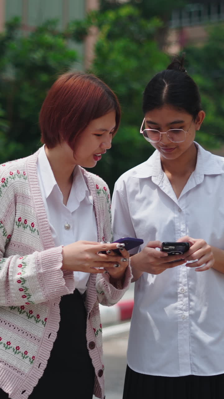 Two women using cell phones outdoors