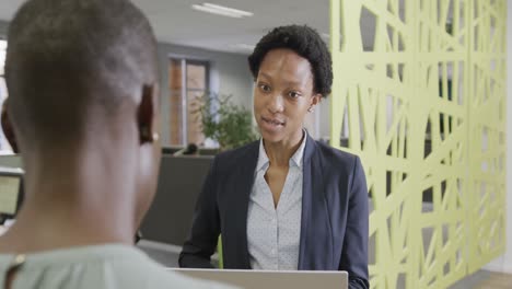 Dos-Empresarias-Afroamericanas-Discutiendo-Trabajo-Y-Usando-Una-Computadora-Portátil-En-La-Oficina-En-Cámara-Lenta
