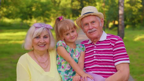 Little-granddaughter-together-with-senior-grandmother-and-grandfather-in-park,-family-relationship