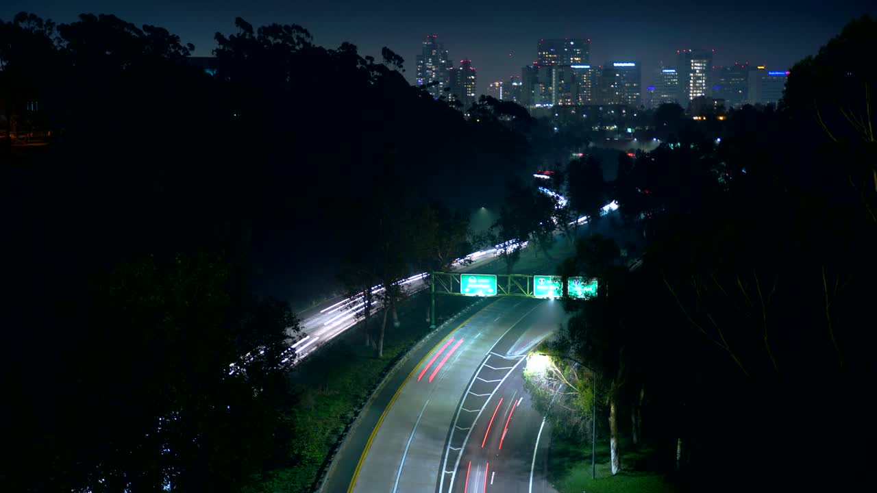 Night Highway Traffic with City Skyline in Background