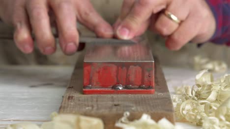 a rack focus macro shot of a carpenter sharpening a chisel on a whetstone in slow motion