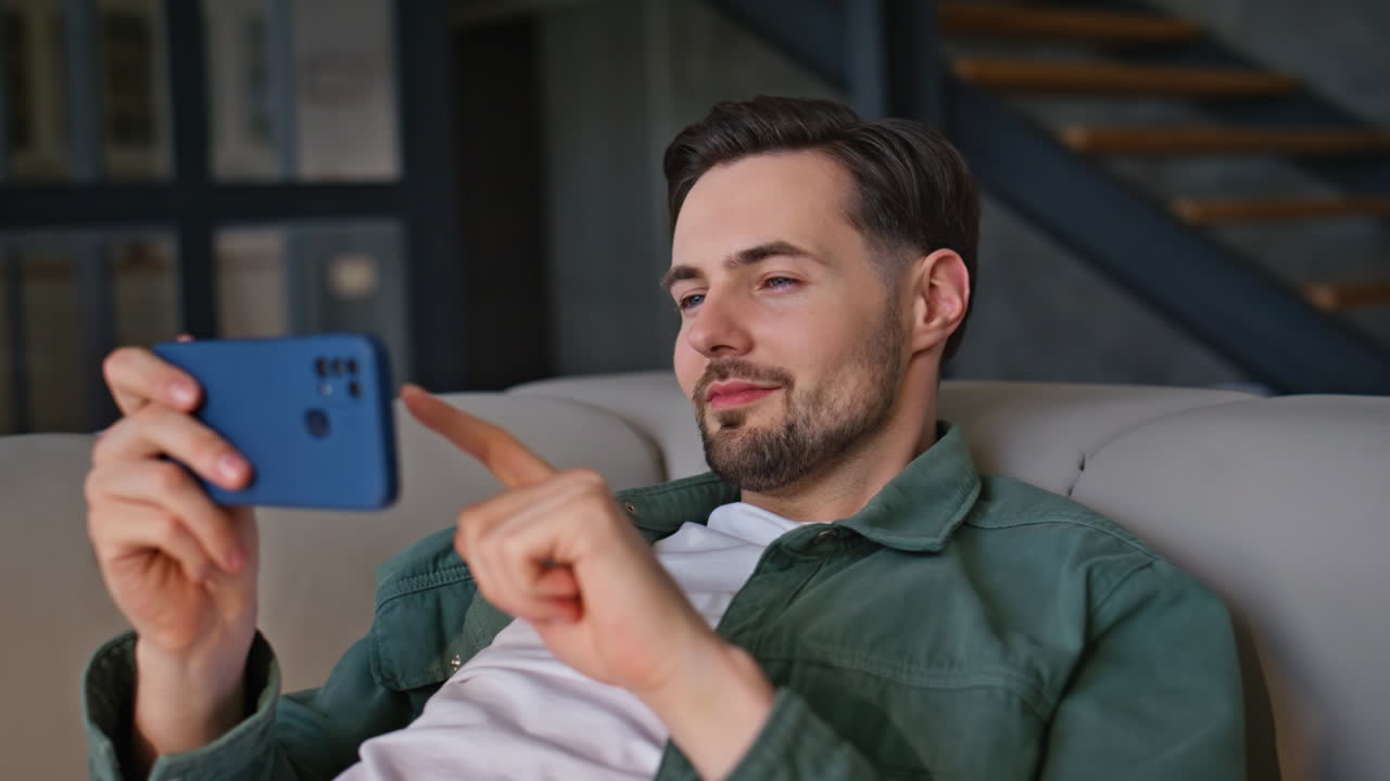 Chilling man watching cellphone lying apartment couch closeup. Guy relaxing