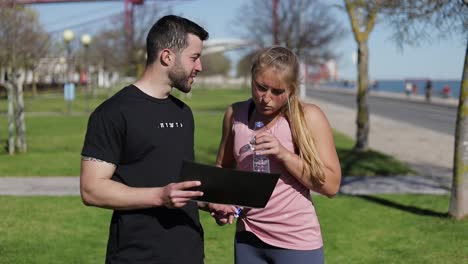 mujer joven reflexiva mirando el plan de entrenamiento con el entrenador.