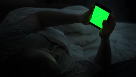 person using smartphone in bed at night