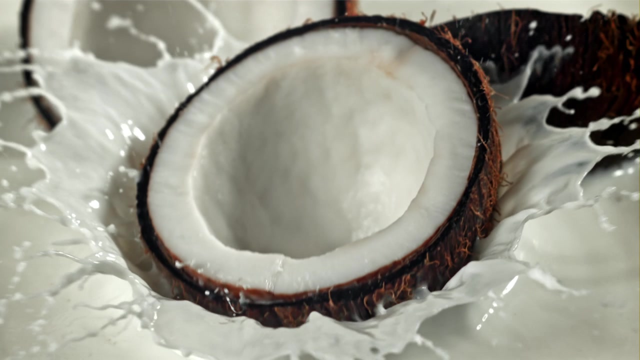 Fresh Coconut Milk Splashing Around a Halved Coconut