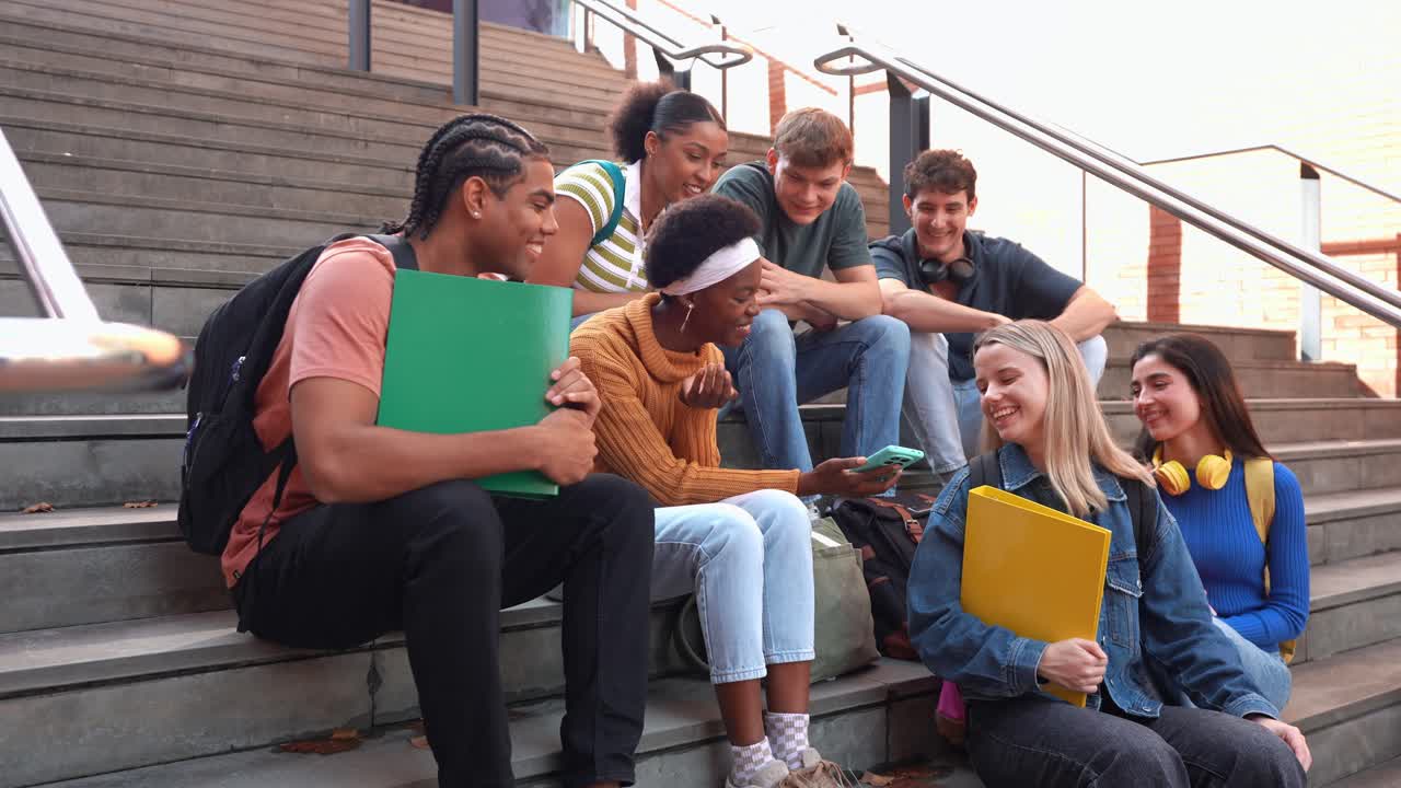 Gruppo eterogeneo di studenti che socializzano e ridono sulle scale del campus
