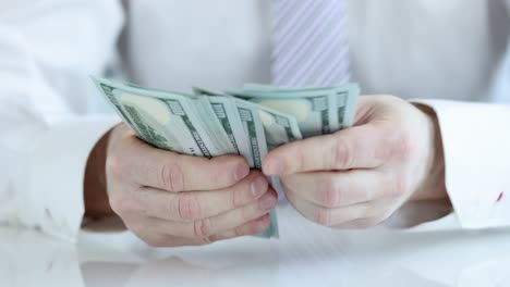 close-up of hands counting hundred dollar bills
