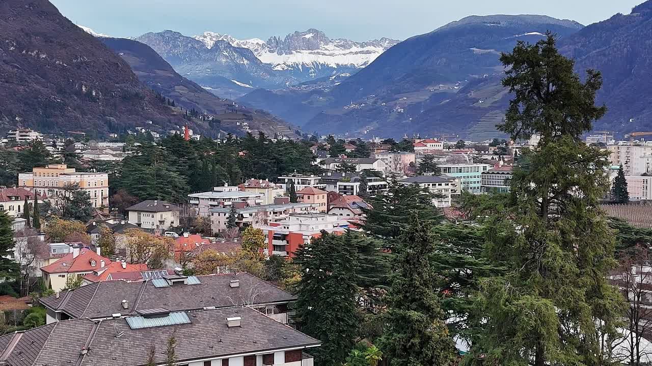 Những ngọn núi vươn lên trên thành phố và cây cối ở dãy Alps của Ý vào mùa đông