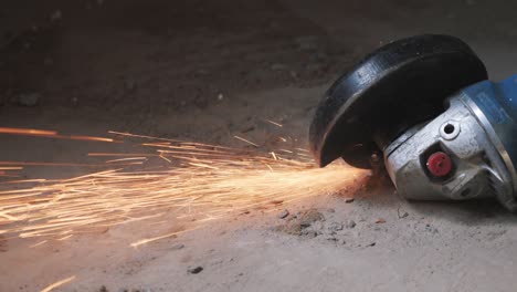 circular metal saw cutting a metal part in concrete floor generation orange sparks. worker cuts metal with orange sparks flying