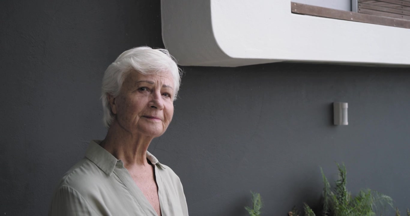 Senior woman standing on deck, turning toward camera after camera sliding past sliding glass door