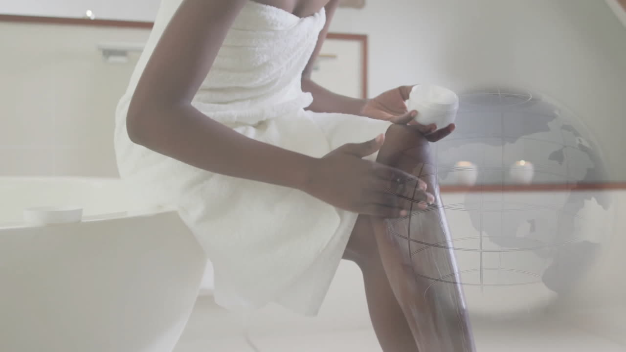 Woman sitting on bathtub edge applying moisturizer on leg in beauty industry, showing globe overlay