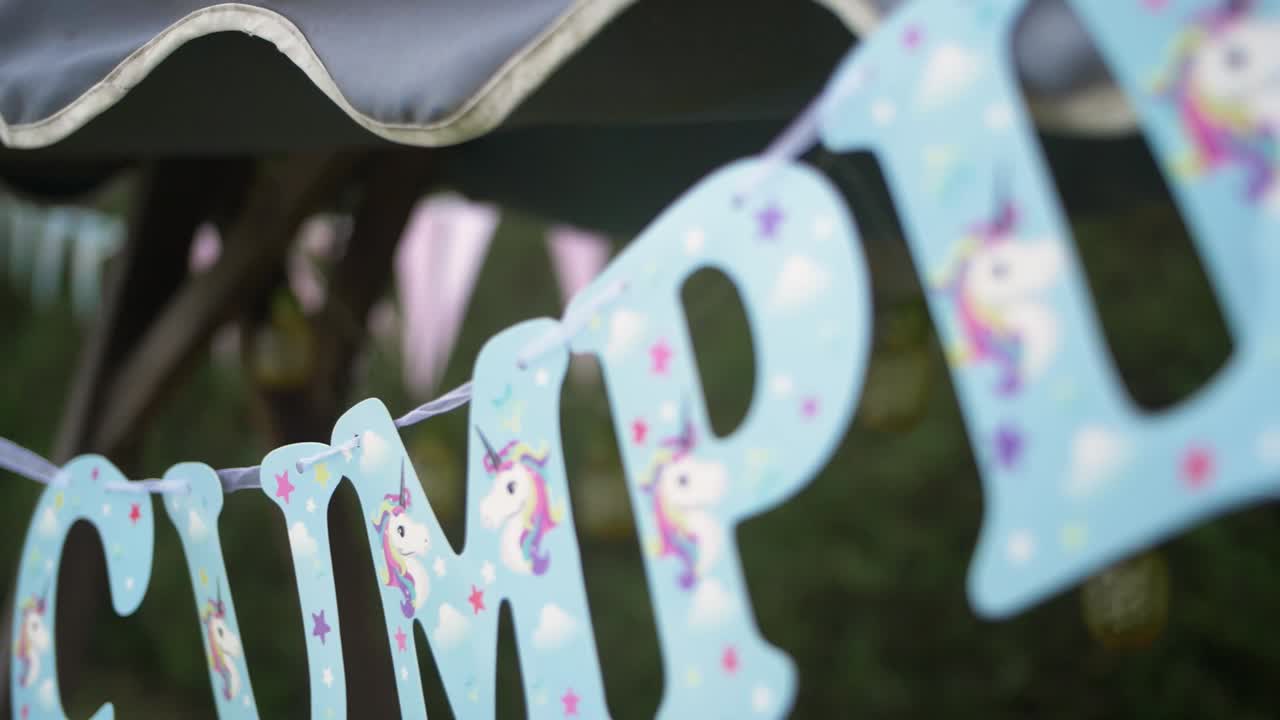 Lettere blu di buon compleanno con unicorni appesi a un evento di festa in giardino