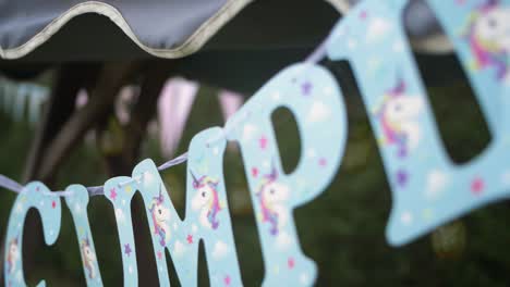 blue happy bithday letters with unicorns hanging in a garden party event