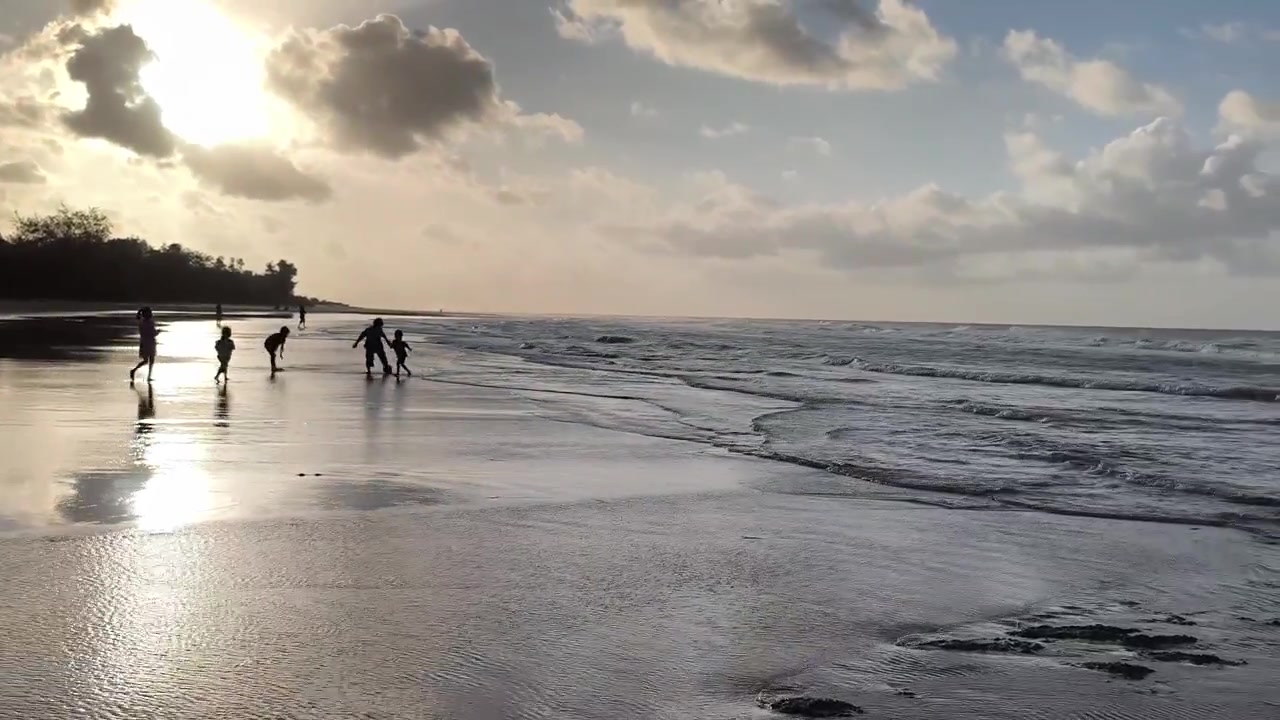 Grupo de Crianças Jogando Futebol em uma Praia Arenosa ao Pôr do Sol.