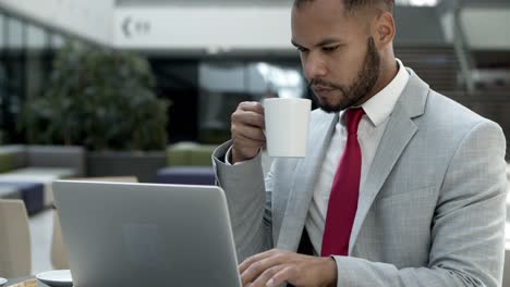 Ernsthafter-Junger-Mann,-Der-Im-Café-Auf-Dem-Laptop-Tippt