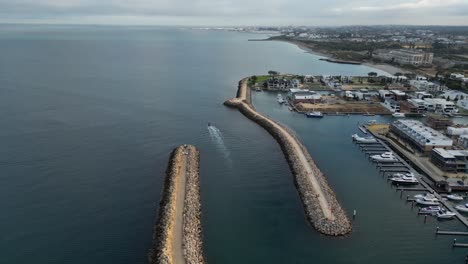 boat-leaving-harbor,-aerial-follow