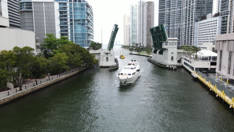 Schöne-Luftaufnahme-Einer-Luxusyacht,-Die-Den-Fluss-In-Der-Innenstadt-Von-Miami-Unter-Der-Brickell-Avenue-Bridge-Befährt